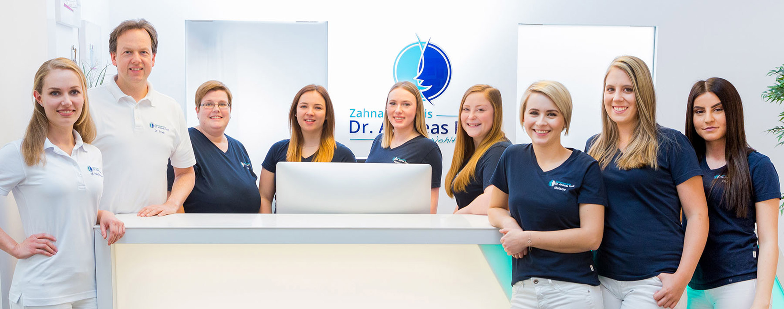 Zahnarzt Dr. Andreas Frodl mit seinen acht Mitarbeiterinnen am Tresen des Empfangs