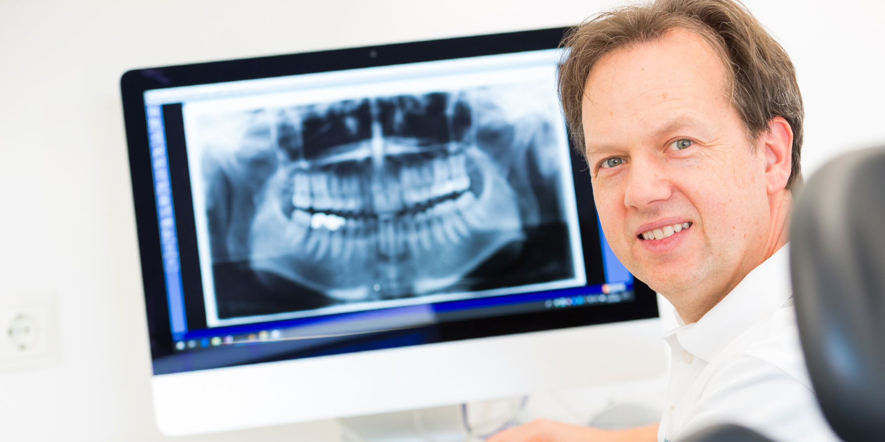 Zahnarzt vor einem Röntgenbild eines Gebisses in der Zahnarztpraxis Dr. Frodl