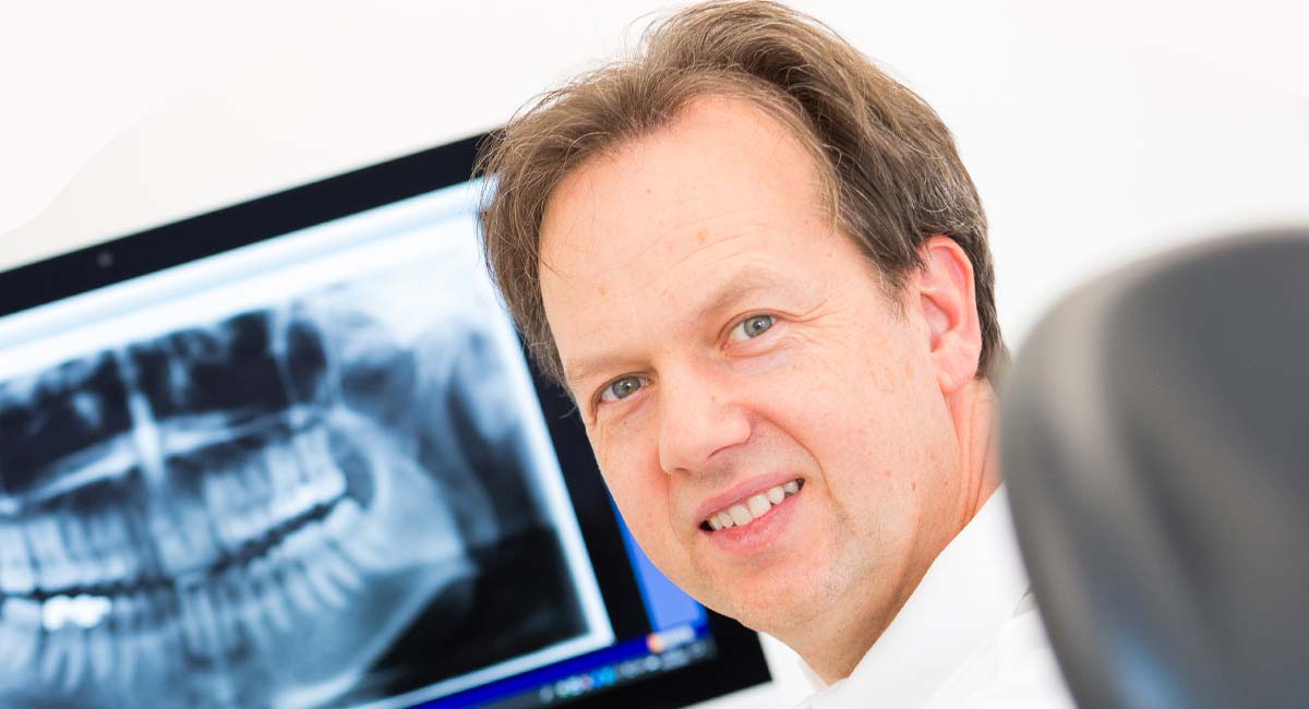 Dr. Andreas Frodl vor einem Röntgenbild von Zähnen